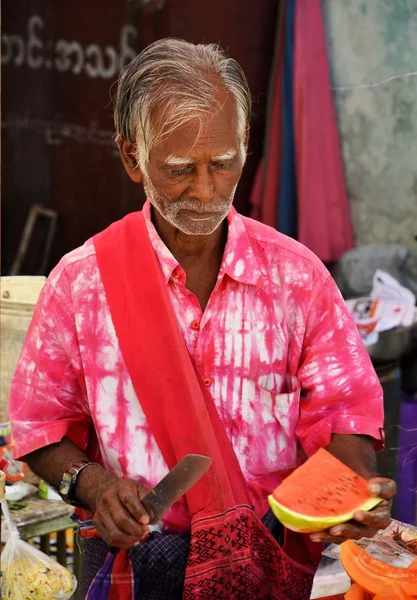 Yangón, Myanmar - 9 de marzo de 2015: Hombre local en rosa cortando sandía en la calle en Yangón —  Fotos de Stock