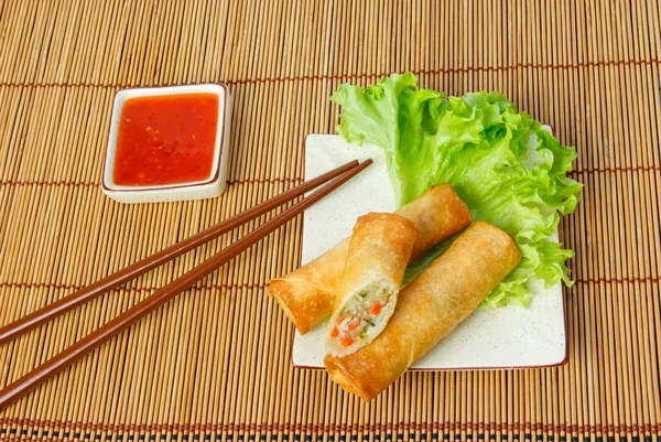 Fried spring rolls, one cut, on a plate with chopsticks — Stock Photo, Image