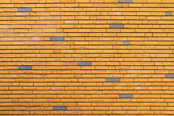 Yellow brick wall interspersed with some gray bricks Stock Photo