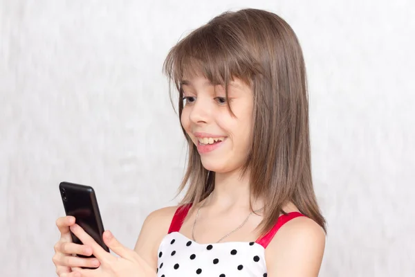 Menina Sorridente Olha Com Interesse Materiais Entretenimento Seu Smartphone — Fotografia de Stock