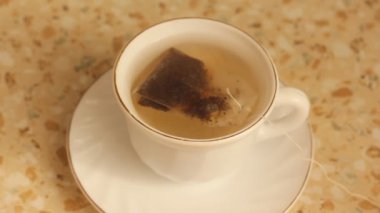 Çay poşetlerini porselen bir fincanda demleme işlemi.