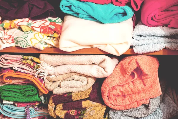 Temiz katlanmış çarşaflar kayan dolabın rafında duruyor..