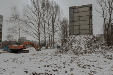 Rusya, Saratov, 18 Mart 2021, Solnechny yerleşim bölgesi, Leninsky bölgesi: Yarısı yıkılmış eski bir konut ve yakındaki bir kazıcı.