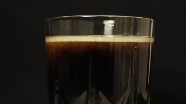 アイスキューブはコーラの炭酸飲料のガラスに投げ込まれます — ストック動画