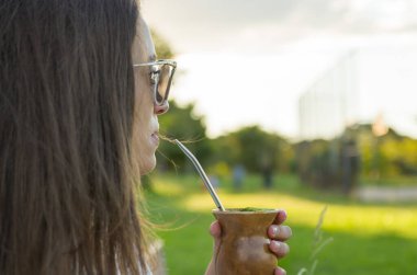Sarışın kadın geleneksel Chimarrao içiyor.