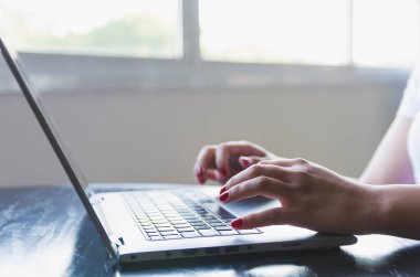 Evde bilgisayar üzerinde çalışan genç bir kadın. İnternette okuyan iş kadını, dizüstü bilgisayar yazılımı, internet sörf bilgileri veya internet mağazasından alışveriş yapıyor.