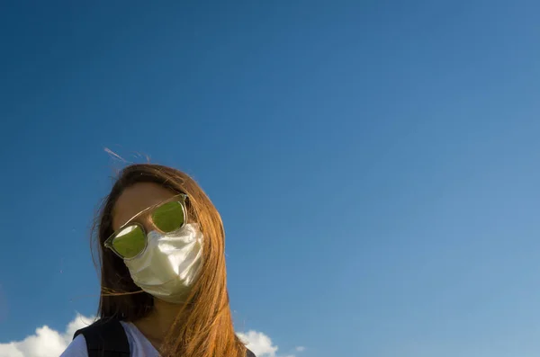Girl wearing face protection mask looking at camera on sunny day