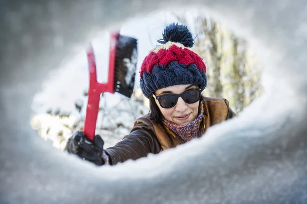 Bella giovane donna pulizia parabrezza di neve — Foto Stock