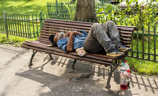 Bezdomny człowiek śpi na ławce w świetle dziennym — Zdjęcie stockowe