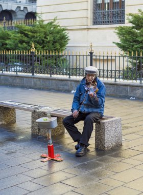 Biraz para kazanmak için zavallı adam bir keman çalıyor