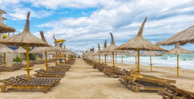 Rüzgarlı bir günde, Teras hasır şemsiyelerle Romen beach san