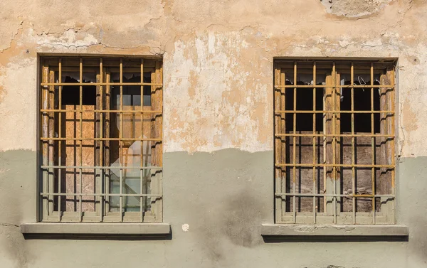 Antiguo edificio con ventanas de cristal roto y barras oxidadas — Foto de Stock