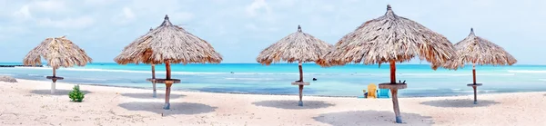 Beach umbrellas on Palm Beach in Aruba island in the Caribbean — Stock Photo, Image