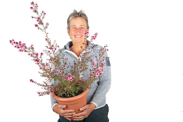 Reife Frau mit einer Vase voller Blumen — Stockfoto