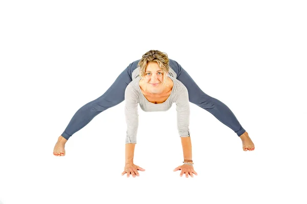 Mujer joven haciendo una postura de yoga sobre un fondo blanco —  Fotos de Stock
