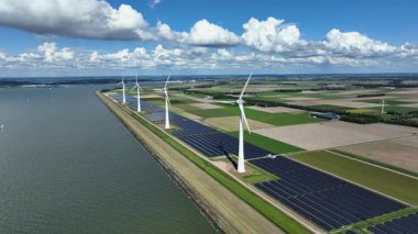 Hollanda 'daki IJsselmeer boyunca rüzgar türbinleri ve güneş panellerinden alınan hava videosu