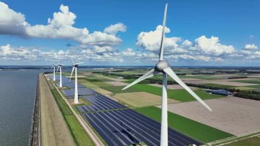 Hollanda 'daki IJsselmeer boyunca rüzgar türbinleri ve güneş panellerinden alınan hava videosu