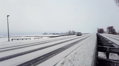 Kışın kar yağışı, düşük görüş mesafesi ve kış sürüş koşullarını gösteren araçlar, bölgesel bir yol boyunca ilerliyorlar..