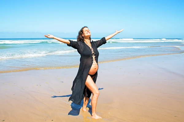 Felice donna incinta sulla spiaggia presso l'oceano Atlantico — Foto Stock