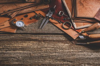 Eski ahşap masadaki deri el aletleri. Deri sanatları atölyesi.