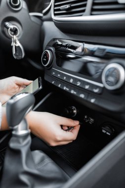 Arabada USB kablosu olan cep telefonu şarj ediliyor. Deri kaplı, otomatik klima kontrol sistemine sahip yepyeni, modern bir arabanın iç görünüşü..