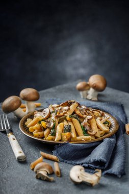 Kızarmış mantarlı makarna, sarımsak ve kabak. Mavi mermer masada İtalyan yemeği.