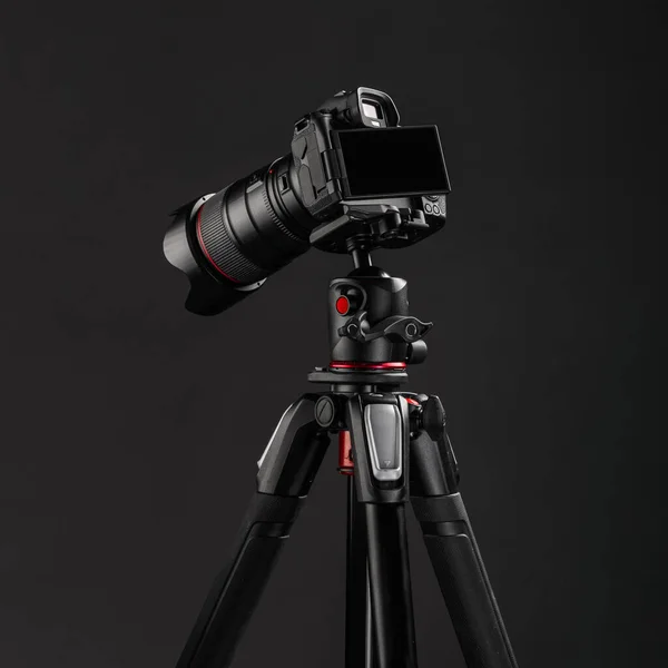 Professional photography equipment, digital mirrorless camera on tripod with dark gray background