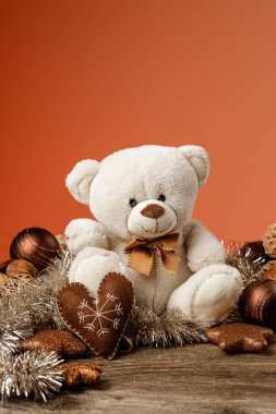Beyaz ya da açık kahverengi sevimli, Noel süslemeleri ve hediyeleri olan oyuncak ayı. Oyuncak peluş ayıyla tatil konsepti ve ahşap masada noel hediyesi..