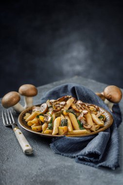 Kızarmış mantarlı makarna, sarımsak ve kabak. Mavi mermer masada İtalyan yemeği.