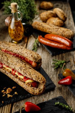 Farklı malzemelerle lezzetli sosisli sandviçler ve koyu arkaplanda kurutulmuş soğan.