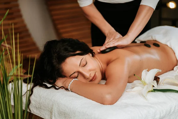 Mulher bonita no salão de massagem com cabelo encaracolado marrom e pele saudável. Conceito de massagista e paciente. — Fotografia de Stock