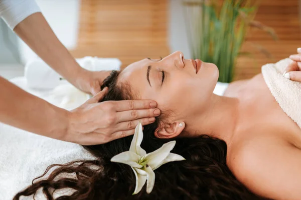 Mulher bonita no salão de massagem com cabelo encaracolado marrom e pele saudável. Conceito de massagista e paciente. — Fotografia de Stock