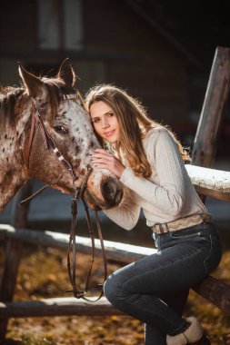 Doğada atıyla poz veren güzel bir genç kız. Güneşli bir sonbahar günü.