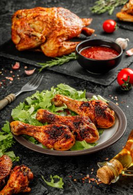 Bir tabak kızarmış tavuk budu ile altın kahverengi kabuklu taze salata ve az pişmiş siyah tabakta servis edilen hayat.