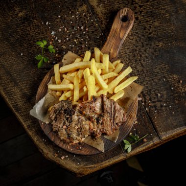 Izgara evi konsepti. Kızarmış, kavrulmuş, kızarmış domuz eti ve patates kızartması eski ahşap kesim tahtasının üstünde..