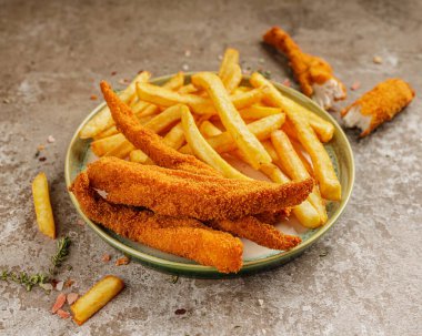 Yeşil seramik tabakta patates kızartmasıyla çıtır çıtır tavuk nuggetları.