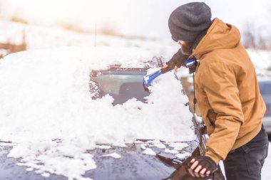 Adam temizleme aracı ile arabadan kar temizler