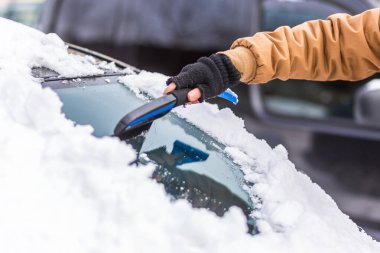 Adam temizleme aracı ile arabadan kar temizler
