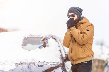 Adam temizleme aracı ile arabadan kar temizler