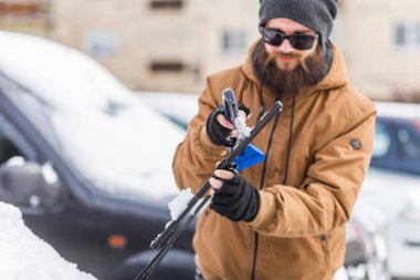 Adam temizleme aracı ile arabadan kar temizler