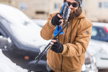Adam temizleme aracı ile arabadan kar temizler