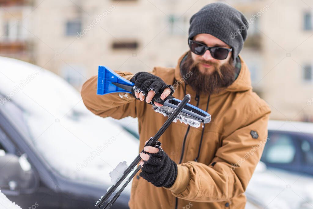 Man clear snow from car with cleaning tool