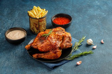 Kızarmış, kahverengi kabuklu, soslu ve patates kızartmalı siyah seramik tabakta servis edilen ızgara bir tavuğun hayatı.