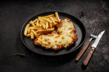 Siyah tabakta fast food. Peynirli ve patates kızartmalı, kahverengi tavuk.