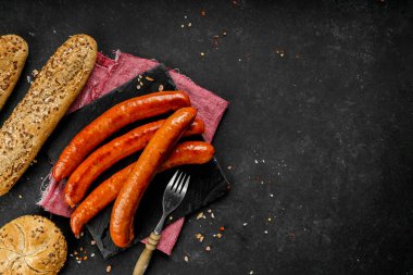 Lezzetli sosisli sandviçlerin düz kompozisyonu ve koyu arkaplanda farklı malzemeler vardı.