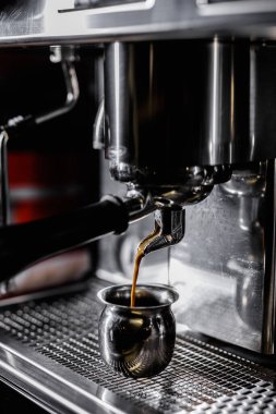 Profesyonel kahve makinesine yakın çekim. Espresso dolduruyorum. Barista taze sıcak kahve hazırlıyor.