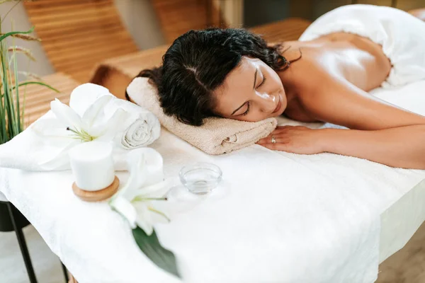 Mulher bonita no salão de massagem com cabelo encaracolado marrom e pele saudável. Conceito de massagista e paciente. — Fotografia de Stock