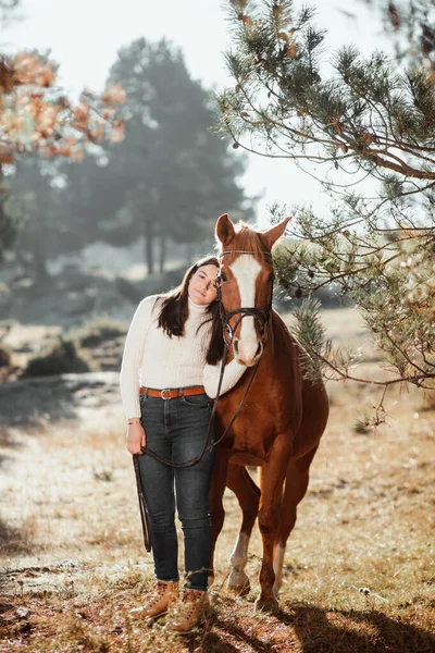 Vacker ung flicka poserar med sin häst i naturen. Solig höstdag. — Stockfoto