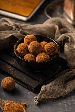 Siyah bir tabakta, kakao tozuyla kaplı sağlıklı malzemelerle ev yapımı lezzetli kakao topları.