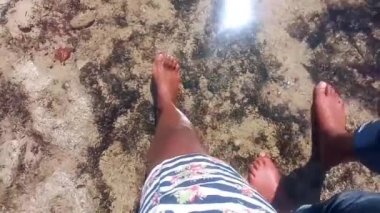 Genç, Afro-Amerikan çift balayında okyanus suyunda birlikte yürüyorlar. Romantik bir kaçamak. Sığ su. Sahilde. Kadın kısa bir elbise, erkek ise kot pantolon giymiş bir adam. Kısmi görüş. Kapat..